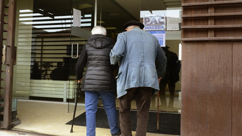 Dos personas mayores entran por la puerta de la residencia.