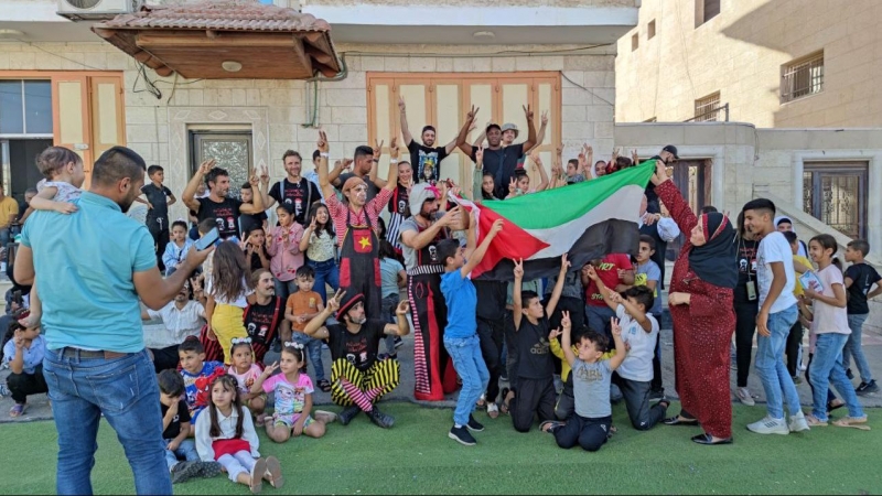 Algunos artistas hondean la bandera de Palestina junto a gente local.