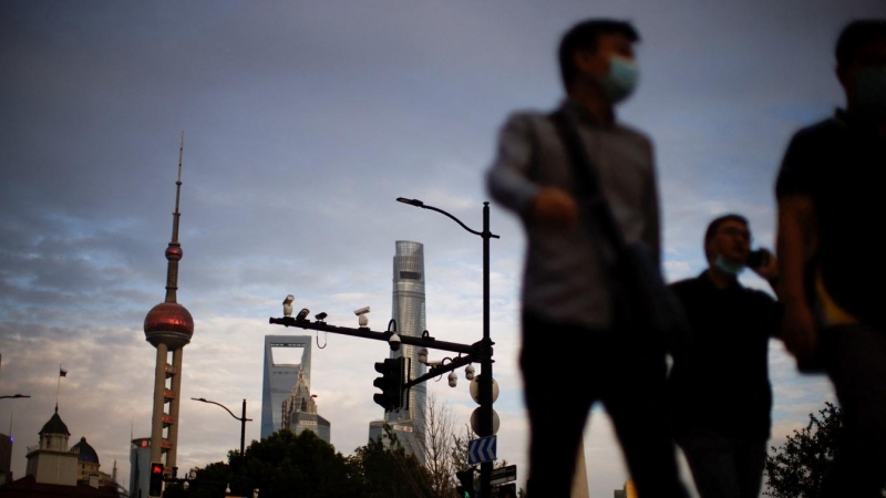 Varias personas caminando por la calle en Shanghái, con la Torre de la Perla Oriental al fondo. REUTERS/Aly Song