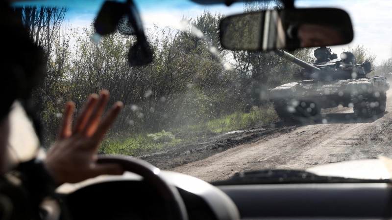 Un conductor pasa junto a un tanque ucraniano que circula por una carretera en la región de Donetsk.