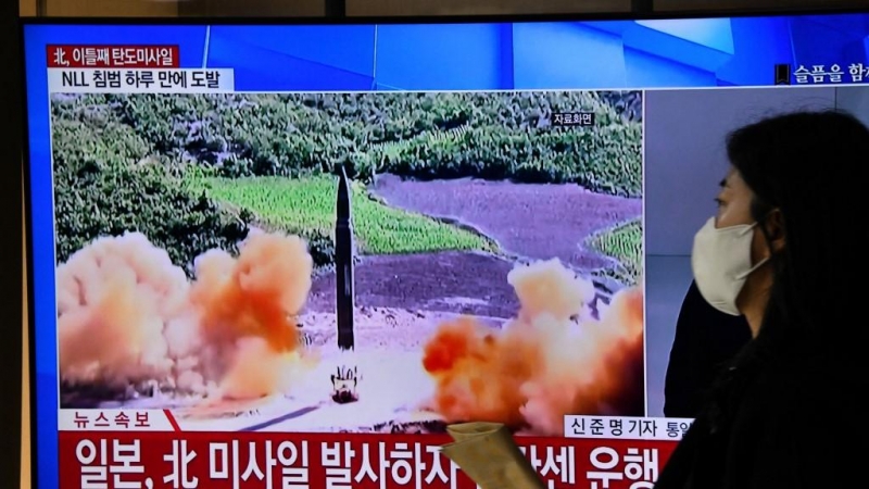 Una mujer pasa frente a una pantalla de televisión que muestra un informativo con imágenes de archivo de una prueba de misiles de Corea del Norte, en una estación de tren en Seúl