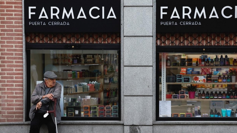 Un hombre mayor sentado en el escaparate de una farmacia en Madrid. REUTERS/Juan Medina