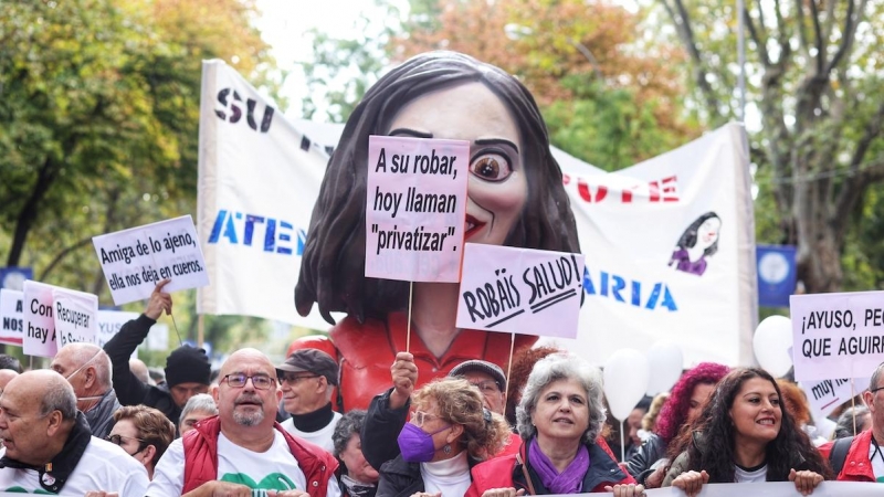 Varias personas portan una cabezuda con la cara de Ayuso durante una manifestación contra el desmantelamiento de la Atención Primaria en la columna que ha salido de Atocha, a 13 de noviembre de 2022, en Madrid.