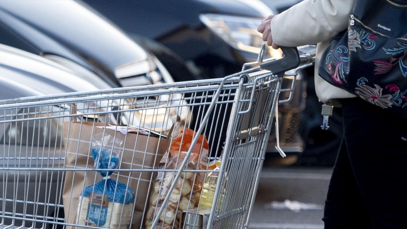 Una mujer sale de un supermercado con un carro de la compra, a 27 de diciembre de 2022