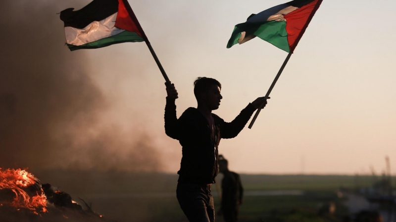 Un manifestante con la bandera de Palestina en la frontera de Gaza protesta tras los últimos ataques contra un campamento de refugiados en Yenín.