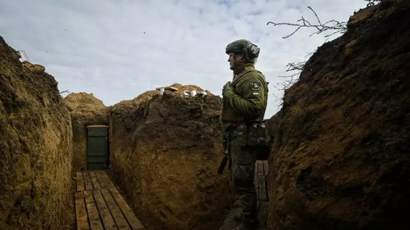 Un soldado ucraniano observando tras una trinchera.