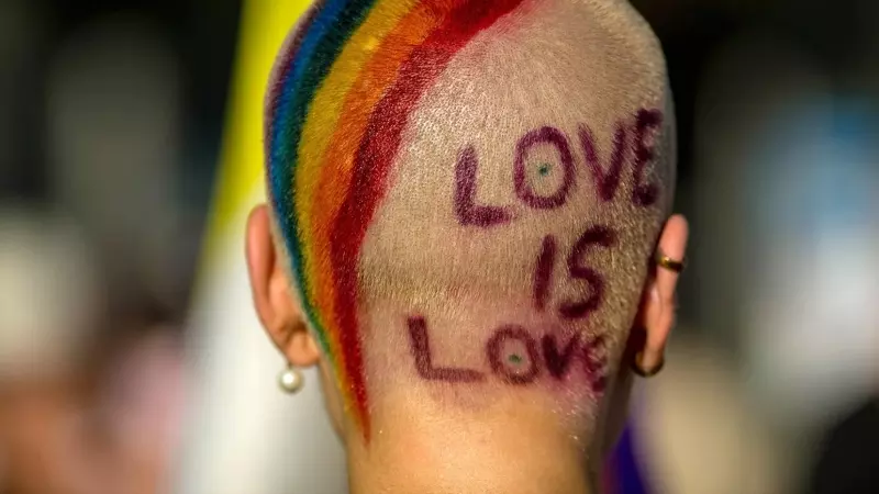 Imagen de archivo de una persona con los colores de la bandera LGBTI en la cabeza y el mensaje 'Love is love'.