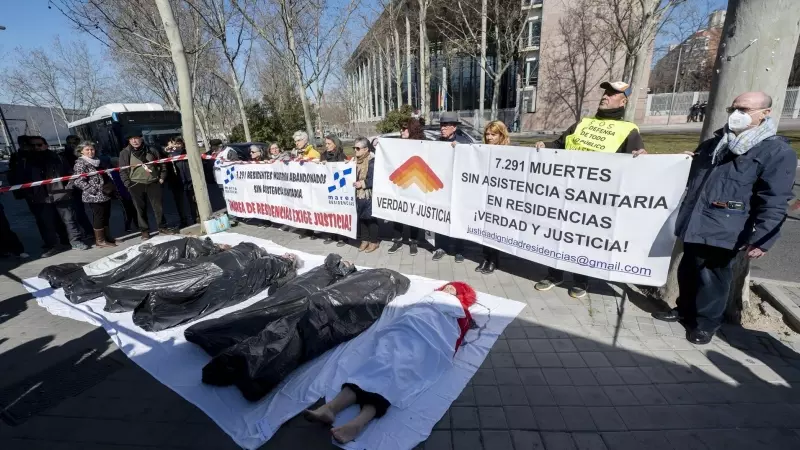 Varias personas participan durante una ‘performance’, de Marea de Residencias y Verdad y Justicia, para protestar por los fallecimientos de mayores durante la pandemia, en las puertas de la Asamblea de Madrid, a 2 de marzo de 2023, en Madrid (España).