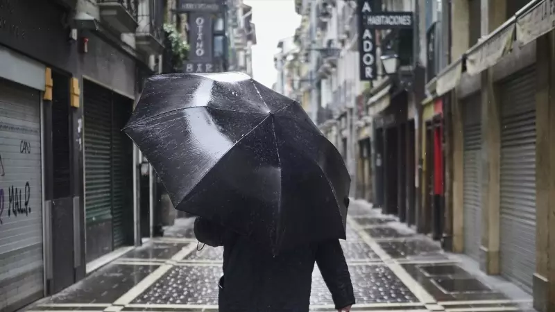 Un hombre camina protegiéndose con un paraguas por la lluvia por el casco viejo de Pamplona durante el Martes Santo a 7 de abril de 2020