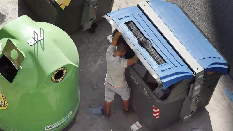 Fotografía de archivo de un hombre buscando en un contenedor de basura.