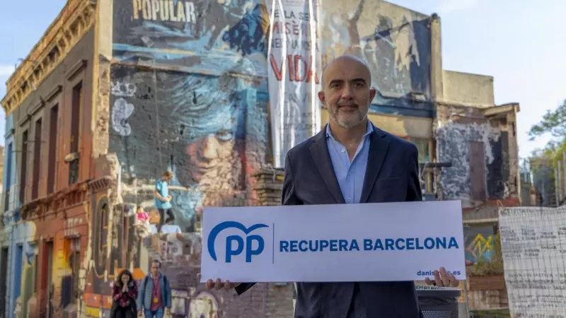 El candidat del PPC a l'Ajuntament de Barcelona, Daniel Sirera, amb el seu lema de campanya front a la icònica casa ocupada de Sant, Can Vies.