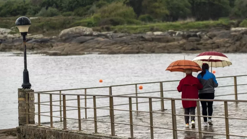 Dos personas caminan con paraguas en la localidad de San Cibrao, Lugo, a 25 de abril de 2023.