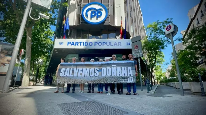 Activistas de Ecologistas en Acción sujetan una pancarta frente a la sede del PP en Madrid para protestar por la gestión de Doñana.