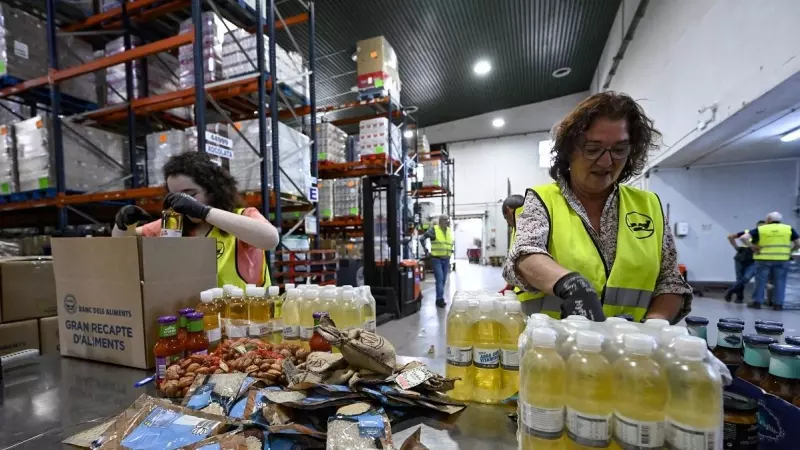 Un par de mujeres organizan los productos que se repartirán en el Banc dels Aliments de Barcelona