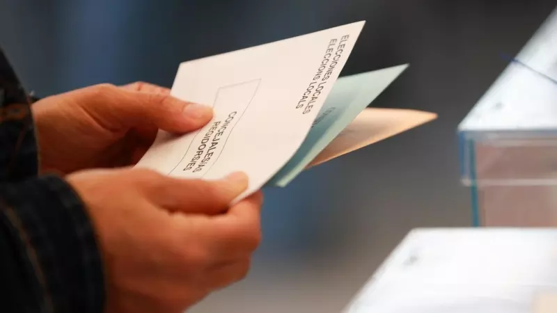 Una persona sostiene papeletas electorales frente a las urnas, a 28 de mayo de 2023