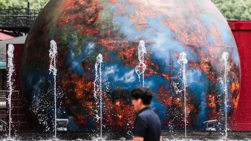 05/07/2023.- Un hombre camina frente a una instalación que muestra una Tierra en llamas en un parque en Daegu, Corea del Sur, a 5 de julio 2023.
