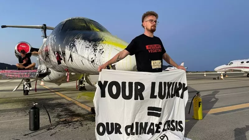 14/07/2023 - Un militante de la asociación Futuro Vegetal sujeta una lona frente al avión privado rociado de pintura, en el aeropuerto de Ibiza, a 14 de julio de 2023.