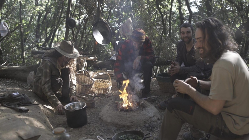 10/2020 - Els quatre joves instal·lats temporalment en un bosc del Montseny preparen menjar al voltant del foc.
