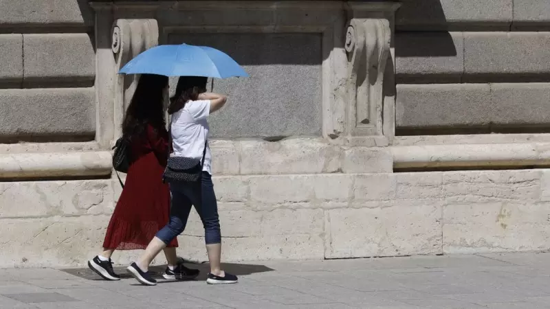 06/08/2023.- Dos mujeres se protegen del sol en Madrid este domingo .
