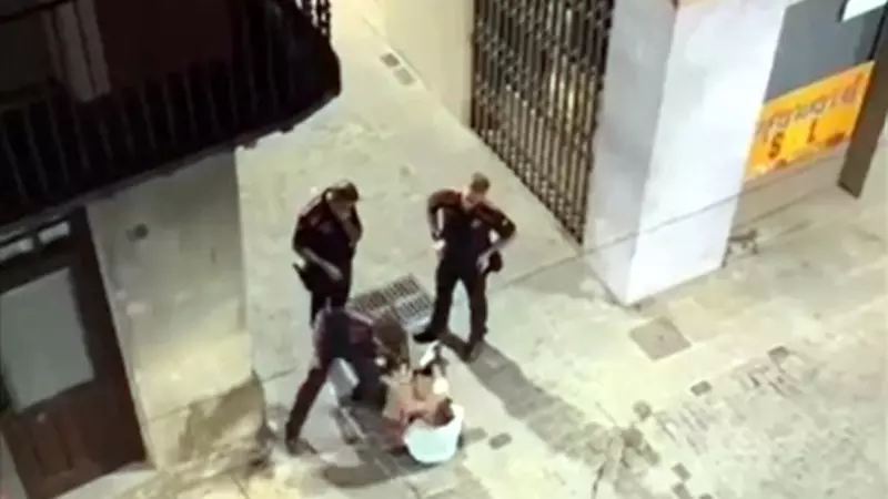 Captura del vídeo del moment en què l'agent dels mossos venta una bufetada a l'home assegut al mig del carrer a Olot