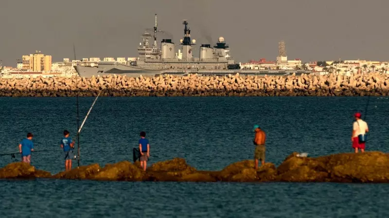 Pescadores en Rota mientras un portaaviones atraca en la base de Rota, a 18 de agosto de 2013.
