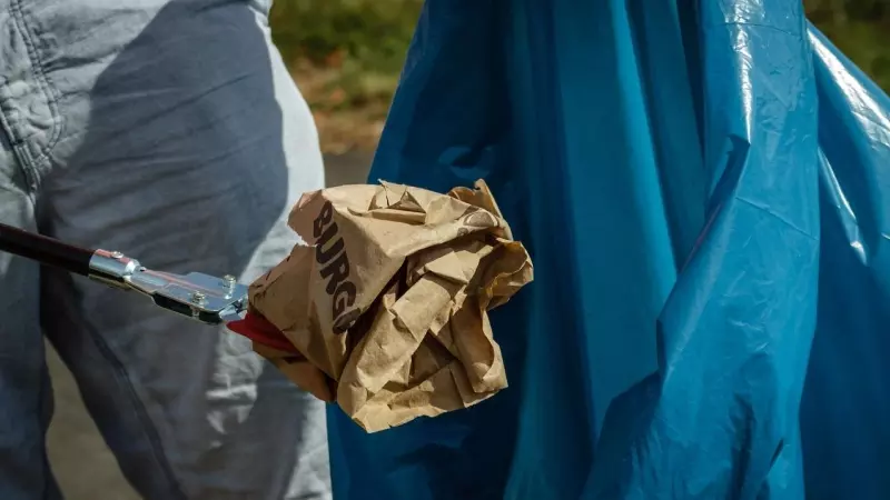 Un hombre tira un envoltorio de comida a la basura.