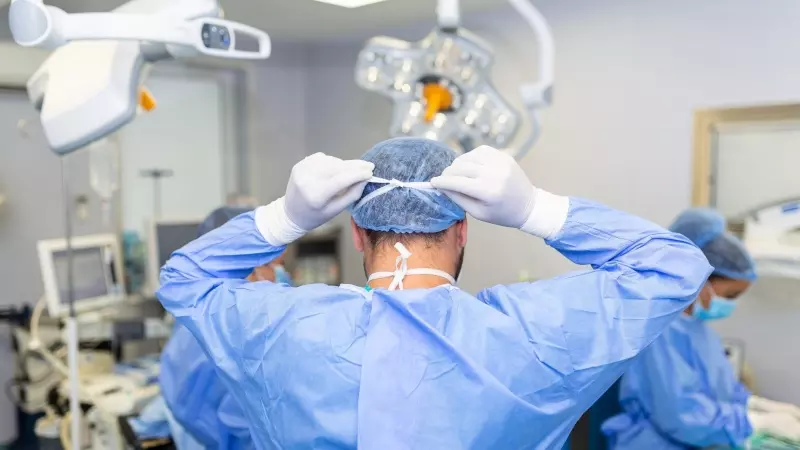 Vista trasera del cirujano masculino con mascarilla quirúrgica en el quirófano del hospital