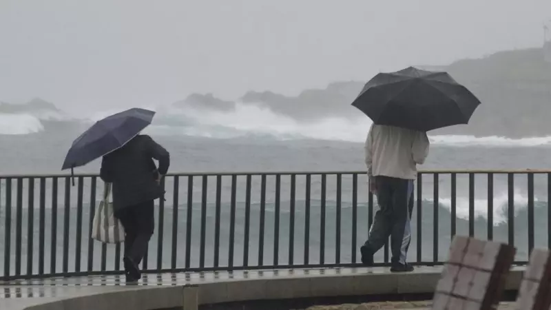 Dos personas caminan con un paraguas al lado de la playa del Orzán, a 22 de enero de 2024, en A Coruña.