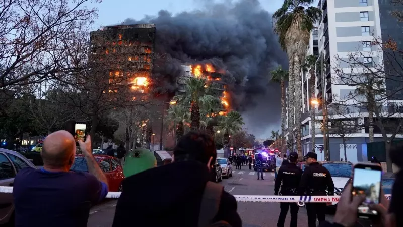 Los vecinos de la zona del edificio incendiado en València tras el cordón que han instalado los servicios de emergencias, a 22 de febrero de 2024.