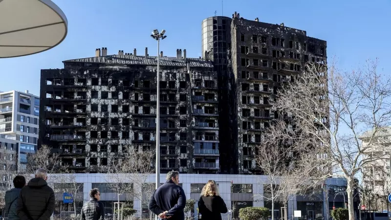 Varias personas observan el edificio incendiado del barrio de Campanar, a 24 de febrero de 2024, en Valencia