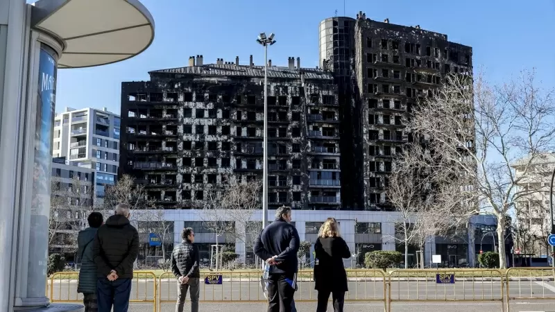 Varias personas observan el edificio incendiado del barrio de Campanar, a 24 de febrero de 2024, en Valencia