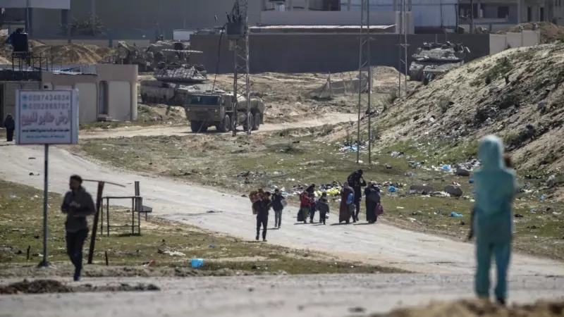 Tanques israelíes patrulla mientras los palestinos desplazados internos caminan hacia Rafah.