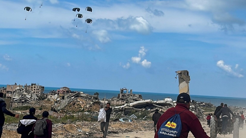 26/3/24- Los palestinos se apresuran hacia la playa para recoger la ayuda lanzada desde un avión, en medio del actual conflicto entre Israel y Hamás, en el norte de la Franja de Gaza, a 25 de marzo de 2024.