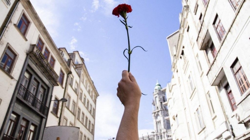 Una mujer sostiene un clavel rojo durante una manifestación para conmemorar el aniversario de la Revolución de los Claveles, a 25 de abril de 2021, en Oporto.