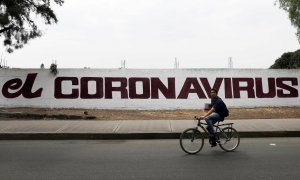 Un ciudadano pedalea con su bicicleta junto a un muro con una pintada que hace referencia al coronavirus. REUTERS/Carlos Jasso