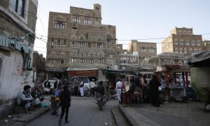 Yemeníes caminan frente a edificios antiguos, un día después de que las partes en conflicto acordaran una tregua de dos meses, en la ciudad vieja de Sana'Äôa, Yemen, el 2 de abril de 2022. Una tregua prorrogable de dos meses en Yemen entró en vigor el 2 d