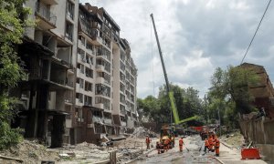 Los trabajadores comunales limpian los escombros frente a un edificio residencial dañado luego de los ataques aéreos rusos en el distrito Shevchenkivskiy de Kyiv (Kiev), Ucrania, el 26 de junio de 2022.
