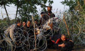 Refugiados sirios cruzan la valla de cuchillas que Hungría ha instalado en su frontera con Serbia, cerca Röszke.- REUTERS / Bernadett Szabo
