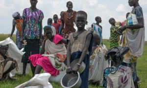 Mujeres y niños desplazados esperan una ración de comida proporcionada por el Programa Mundial de Alimentos. - AFP