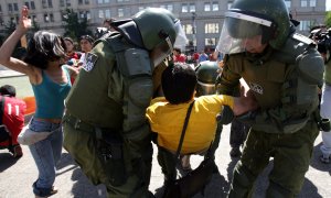 Policías antidisturbios arrestan en 2008 a un activista durante una manifestación donde indígenas mapuche tiñeron el agua de la fuente frente al rojo de La Moneda (Santiago),  simbolizando la muerte de un mapuche. / AFP - MARTIN BERNETTI