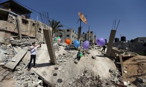 Un hombre palestino cuelga globos sobre las ruinas de una casa que fue destruida en los recientes ataques aéreos israelíes | Reuters