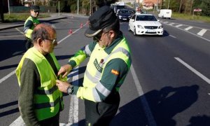 Un guardia civil coloca un chaleco reflectante a un peatón. / EFE