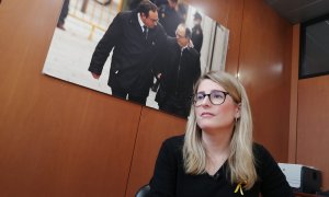 Elsa Artadi durant l'entrevista realitzada al Parlament amb una foto de Josep Rull i Jordi Turull al fons.