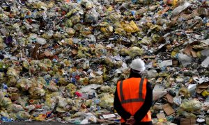 Un operario observa parte de los residuos prensados en una planta de reciclaje. /AFP