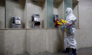 Un operario limpia los teléfonos de la estación de Gwanghwamun, en Seúl, Corea del Sur. - EFE