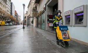 Una trabajadora del servicio de Correos realiza su trabajo por las calles casi desiertas de Zaragoza el pasado lunes. EFE/Javier Cebollada