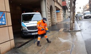 Un treballador netejant amb aigua a pressió davant l'accés a l'hospital de Sant Pau i Santa Tecla de Tarragona.