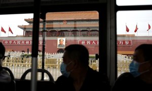Personas con mascarilla pasan en un autobús por delante de la Ciudad Prohibida, en la Plaza de TTiananmen, en Pekín.. REUTERS/Tingshu Wang