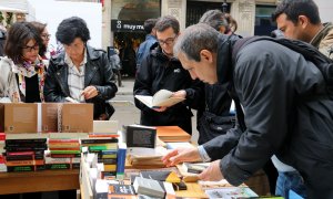 Lectors remenen llibres a una parada de la Rambla de Catalunya de Barcelona durant el dia de Sant Jordi. Imatge del 23 d'abril de 2019. (Horitzontal). ACN | Mar Vila