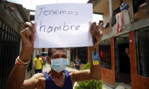 Un hombre es visto con un cartel mientras protesta este jueves en Cali (Colombia). Decenas de personas salieron de sus casas haciendo sonar cacerolas para reclamar a la alcaldía por la falta de ayudas y alimentos en medio de la cuarentena por la emergenci